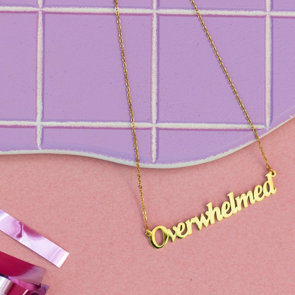 Gold necklace with the word "Overwhelmed"