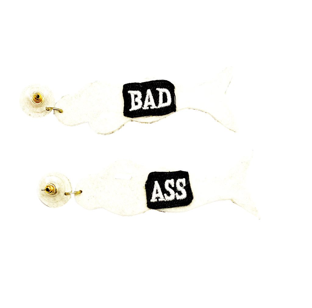 Stylish ivory earrings featuring a mermaid motif and a bold "Bad Ass" patch, ideal for adding edge to your look.