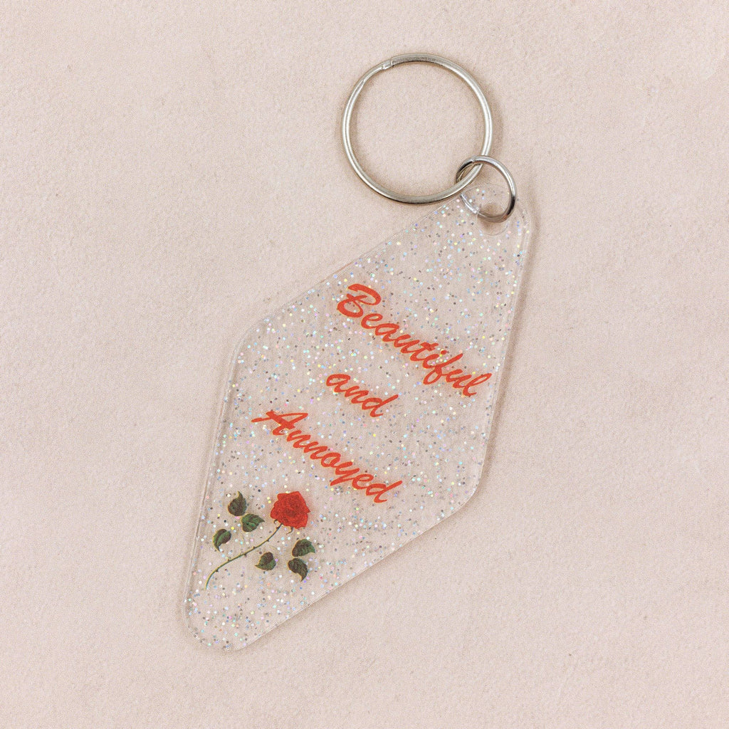 Glittery keychain with rose and text design.