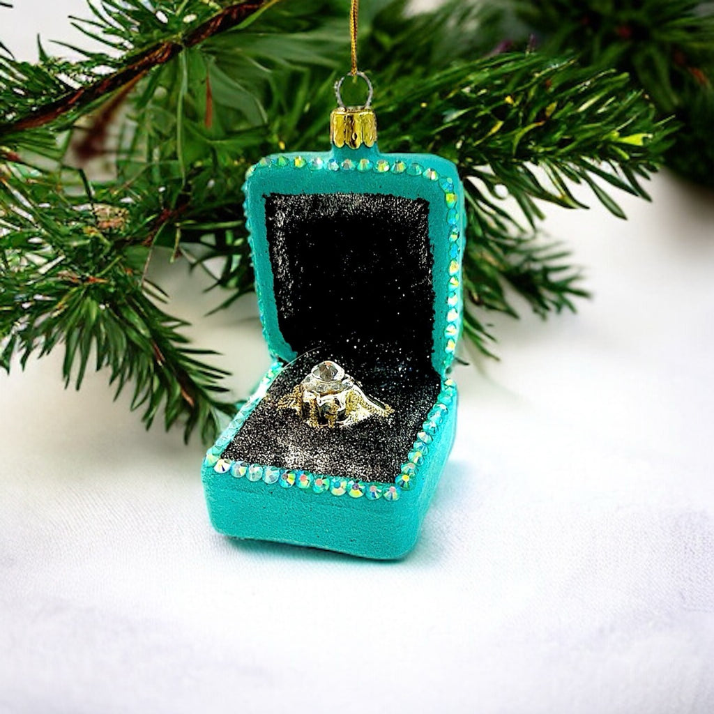 Festive glass ornament shaped like a diamond ring in a box, adding sparkle to your Christmas tree.