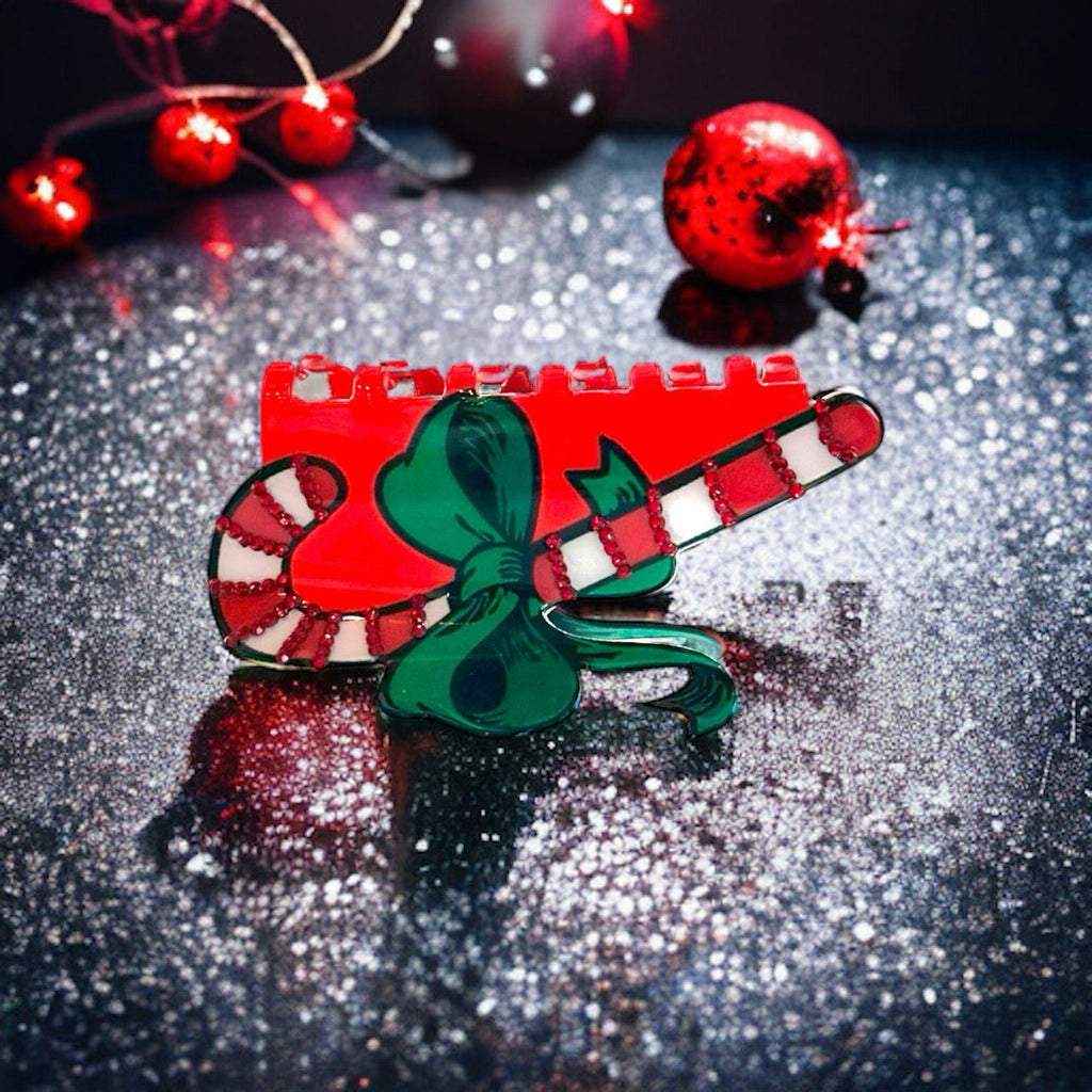 Red and white candy cane-striped hair clip featuring a bow at its center and a two-pronged alligator clip at its base. 
