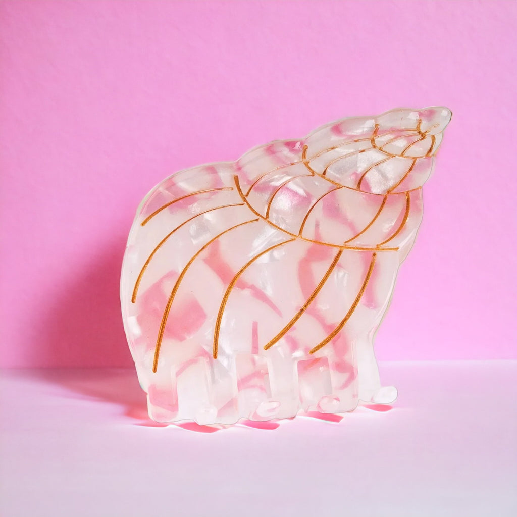 Light pink conch shell hair clip displayed against a pastel background, perfect for adding a beachy touch to any hairstyle.