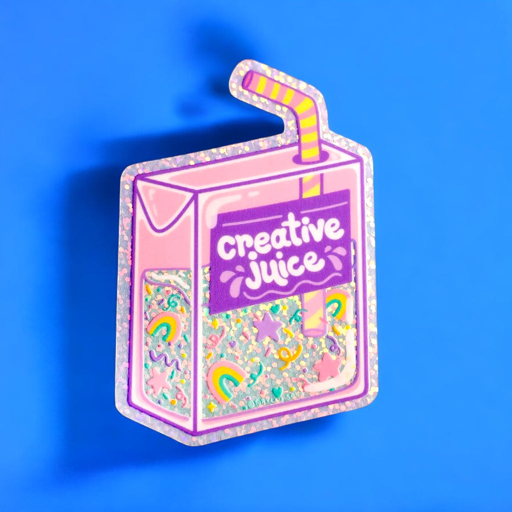 A colorful glittery sticker shaped like a juice box with "Creative Juice" written on it, decorated with rainbows, stars, and pastel confetti.