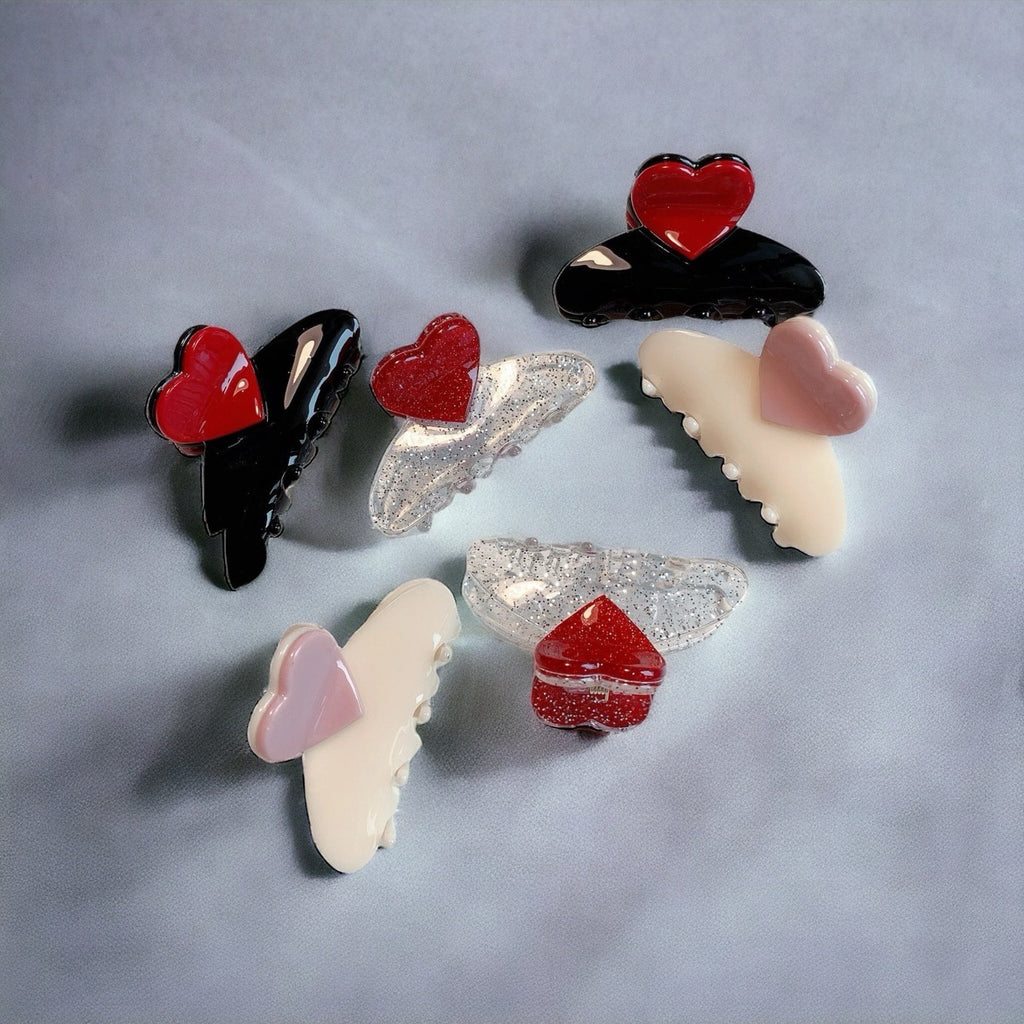 Pair of heart-shaped hair clips with pastel pink and white colors, featuring glittery heart designs.