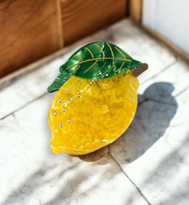 Cute lemon-shaped hair claw with vibrant yellow design and green leaf, perfect for summer outfits and vacations.