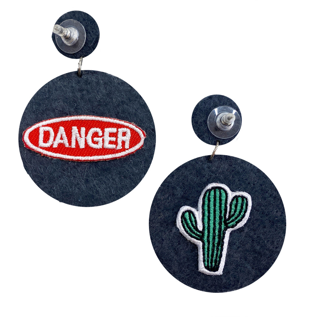 Eye-catching silver earrings with a starburst design, complemented by unique "Danger" and cactus patches.