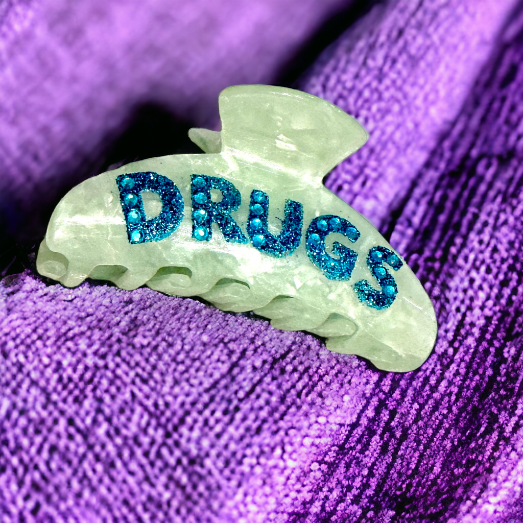 Green acetate hair clip featuring rhinestone "DRUGS" lettering, perfect for a 90s look.