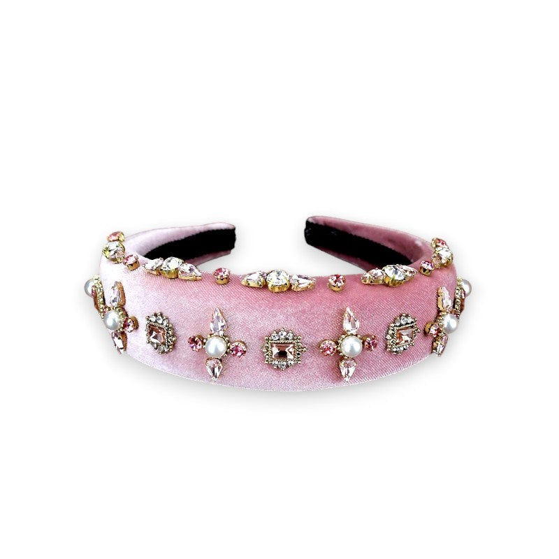 Velvet pink headband resting on its side with pearls and rhinestones.