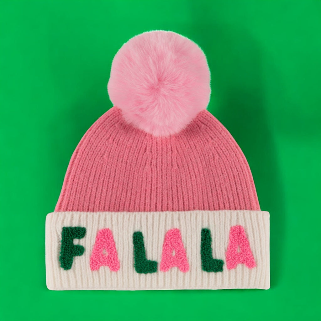 Pink knit hat with a fluffy pink pom-pom and white cuff featuring the text "Fa La La" in green and pink letters.