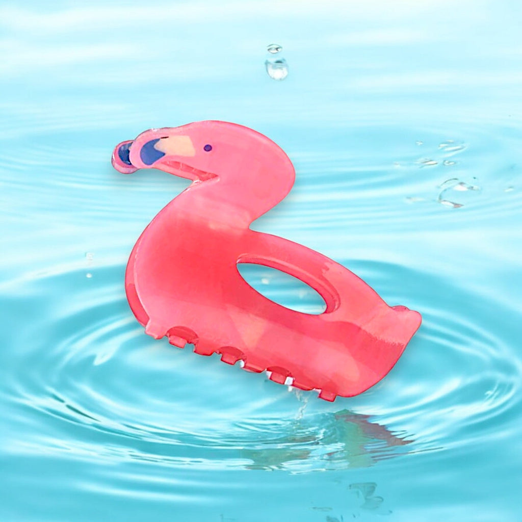 A pink flamingo hair clip floating on water.