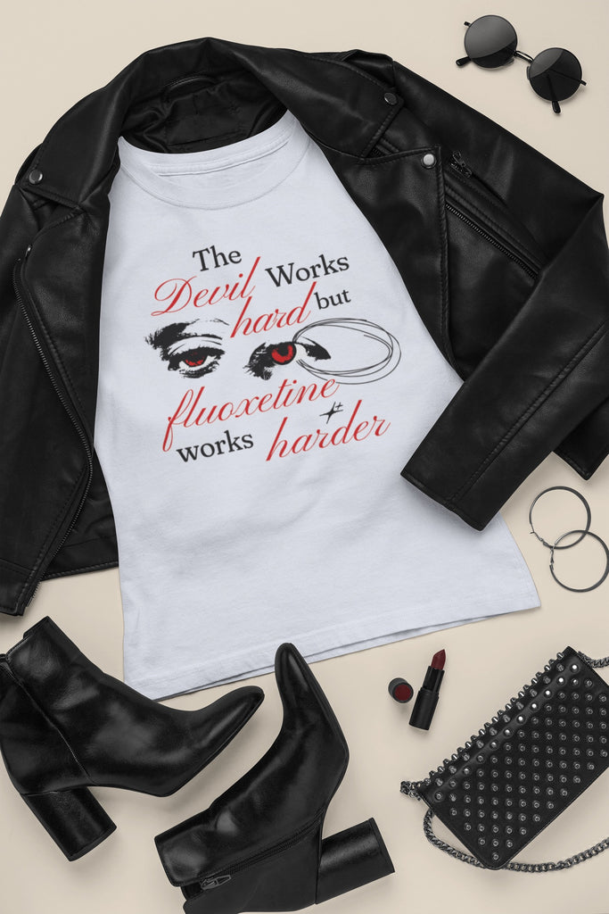 Close-up of a trendy graphic tee featuring the phrase "The Devil Works Hard but Flouxetine Works Harder" in black and red font.