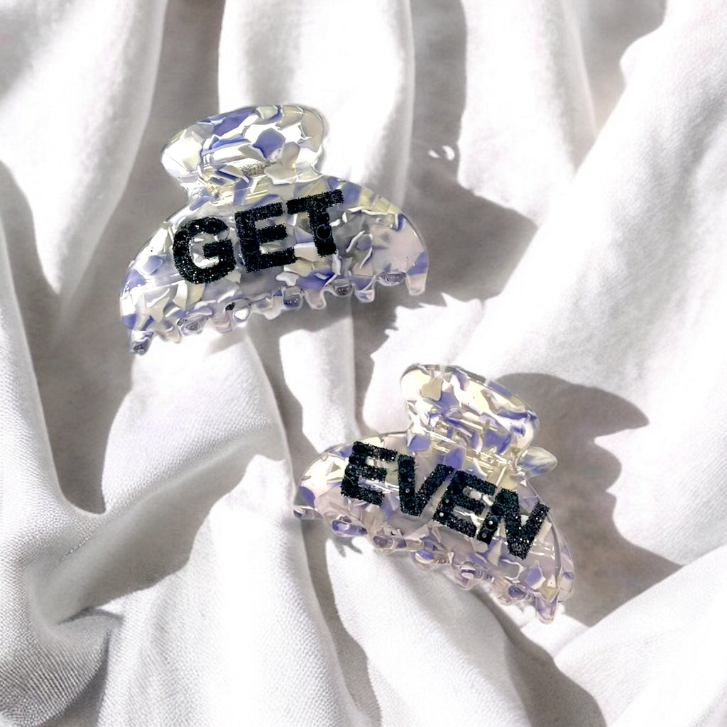 Bold statement hair clip with iridescent finish and glitter "Get Even" lettering, designed for thick hair styling.