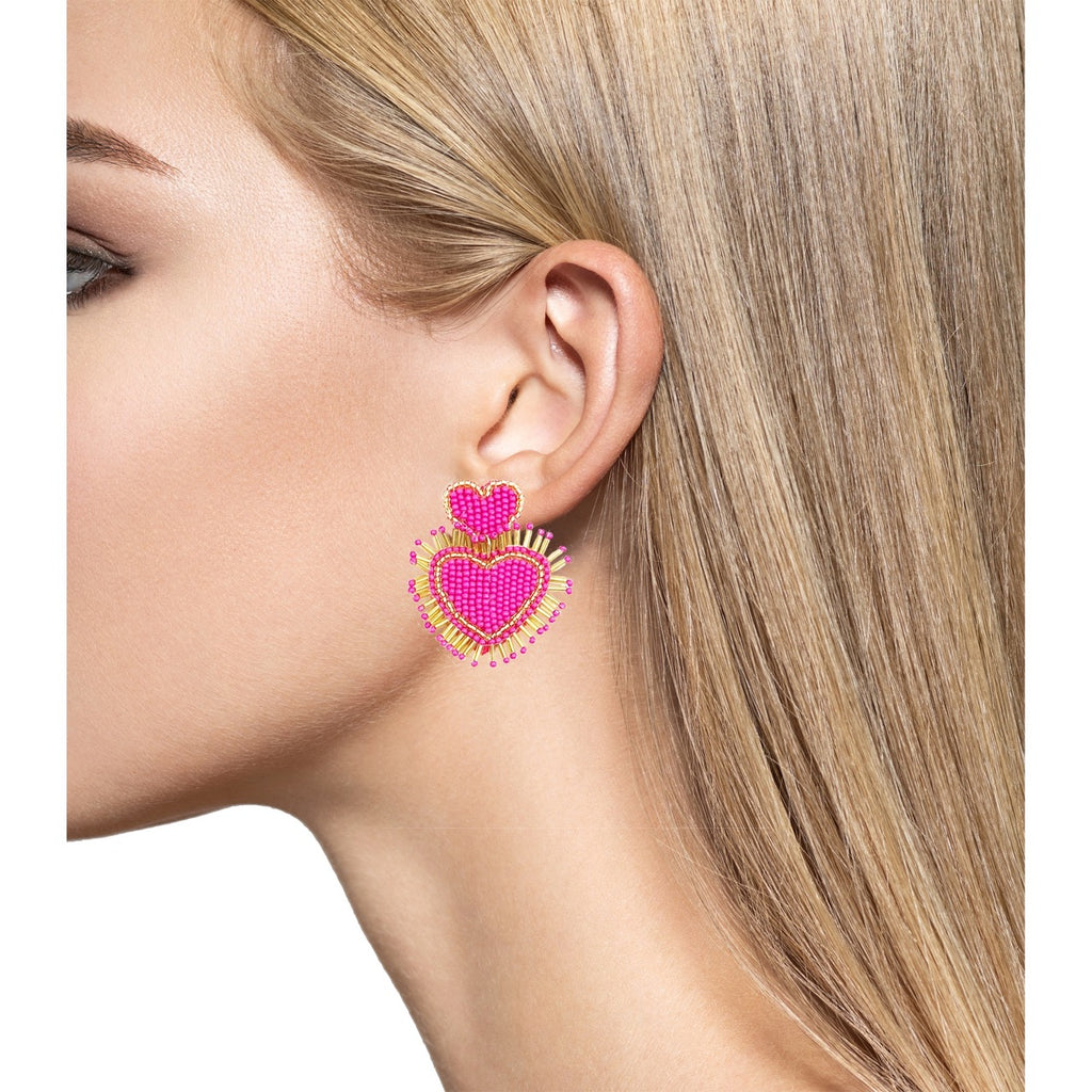 Bold and playful fuchsia pink earrings with a double heart design, gold fringes, and a "Happy Leaves" patch.