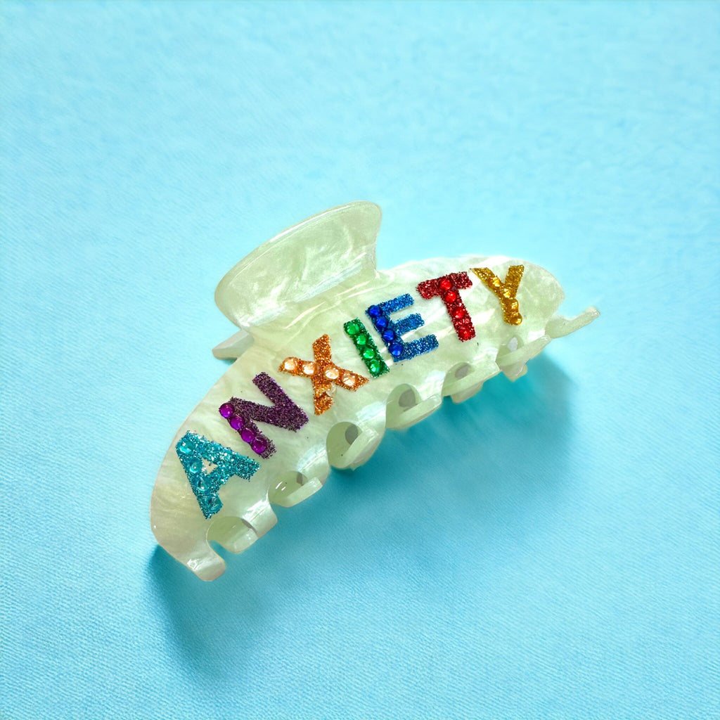 Unique hair accessory with rainbow rhinestone "ANXIETY" text on a green clip, ideal for adding humor and style.