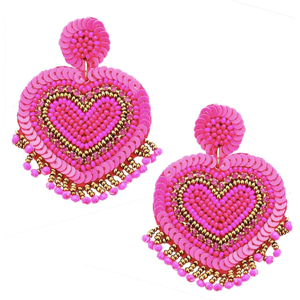 Multidimensional fuchsia earrings featuring heart shapes and pop-art patch designs.