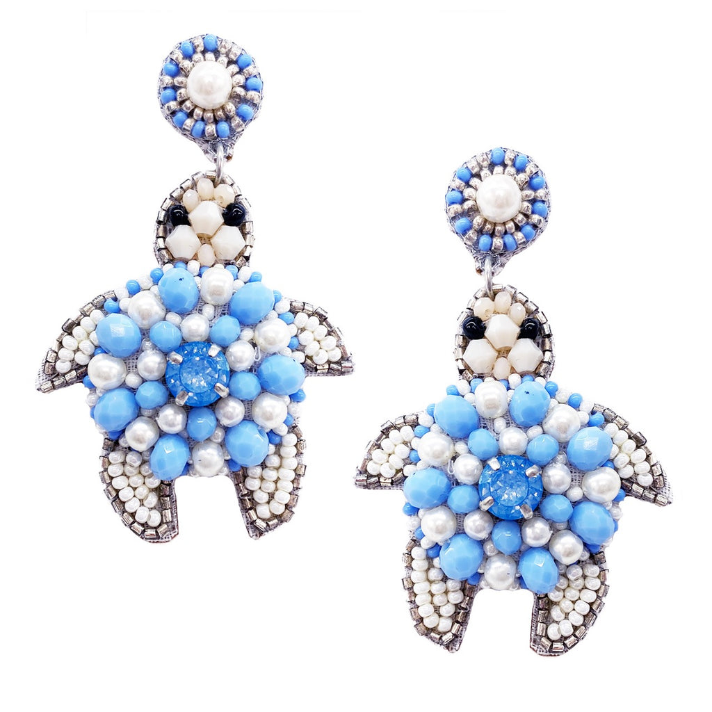 Coastal-themed earrings featuring a turtle design with blue beads and a playful "Good Vibes" patch.