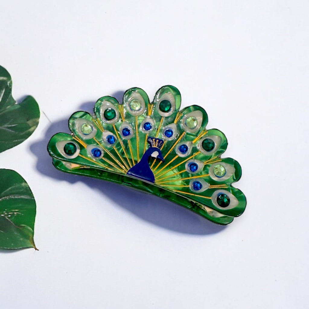 An image of an elegant peacock-inspired hair clip featuring vibrant blue and green stones in a unique design, perfect for adding a touch of glamour to any outfit.
