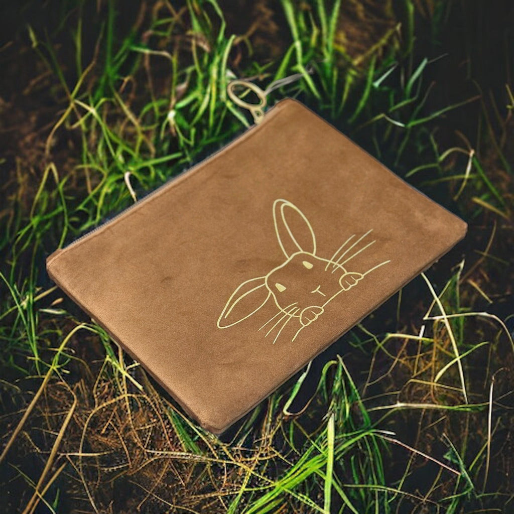 Detailed tan colored bunny faced suede pouch sitting on a bright yellow background showcasing the 3-D bunny ears and sparkling gold colored studs.