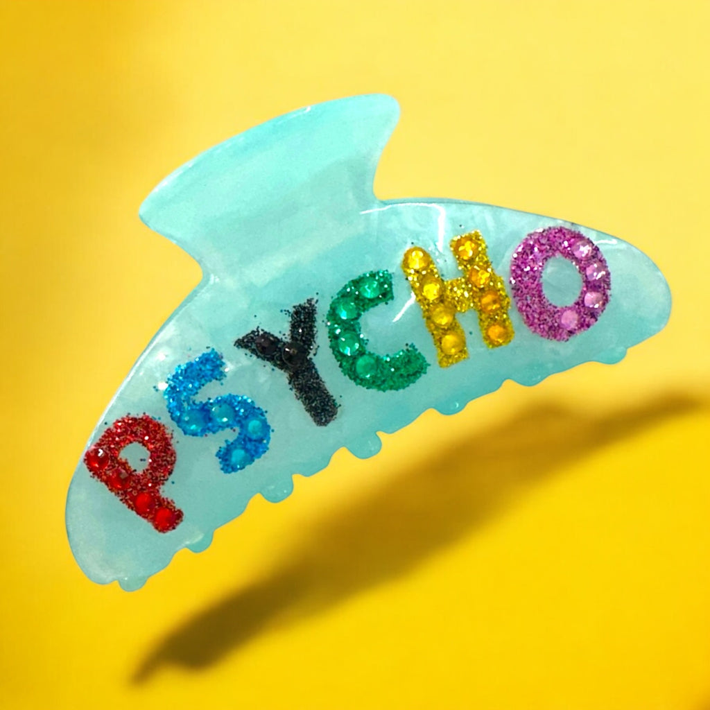 Blue marble "Psycho" hair clip with rainbow glitter letters and strong grip for thick hair.