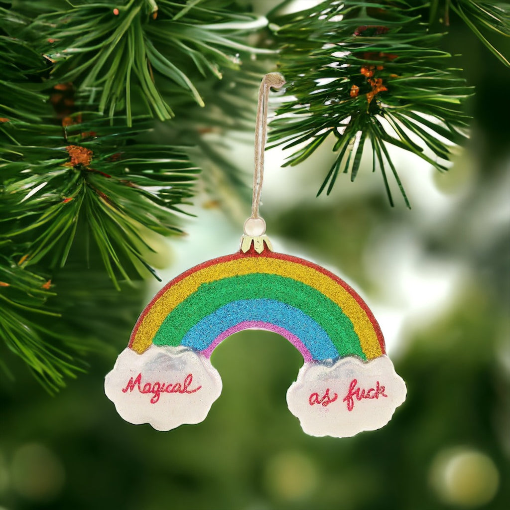 Colorful rainbow Christmas ornament with "Magical as f***" written on clouds, perfect for adding fun to holiday decor.