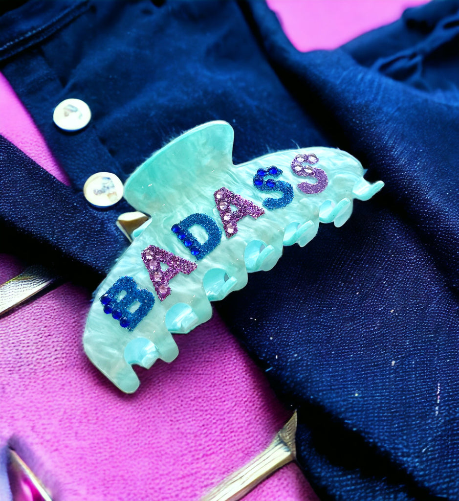 Bold and flashy hair clip with "BADASS" rhinestone lettering on blue acetate, ideal for statement-making styles.