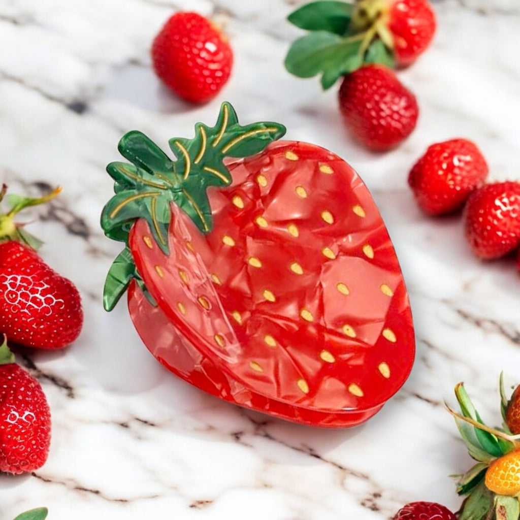 Vibrant strawberry hair clip on a white surface.