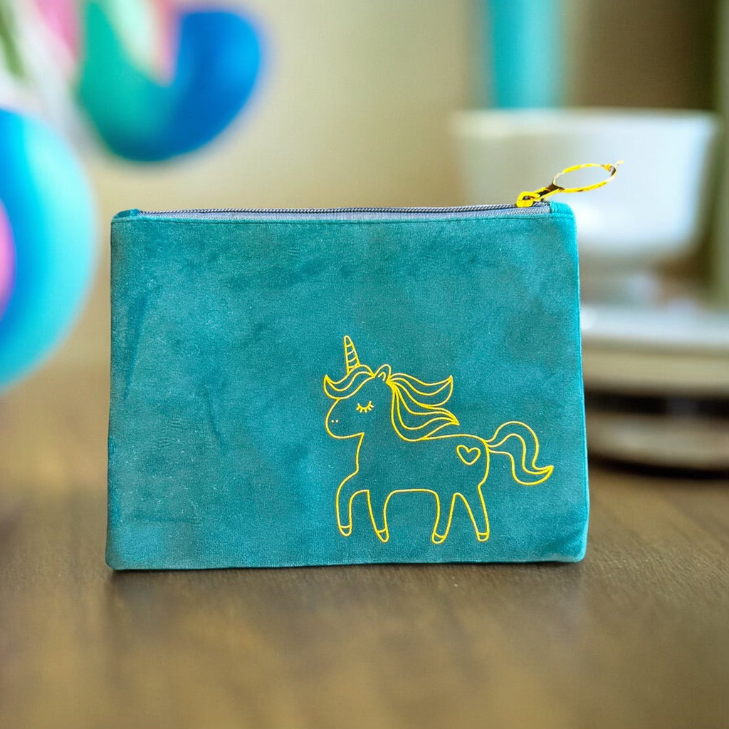 Plush rainbow unicorn makeup bag in a luxurious faux suede with a gold zipper on a white background
