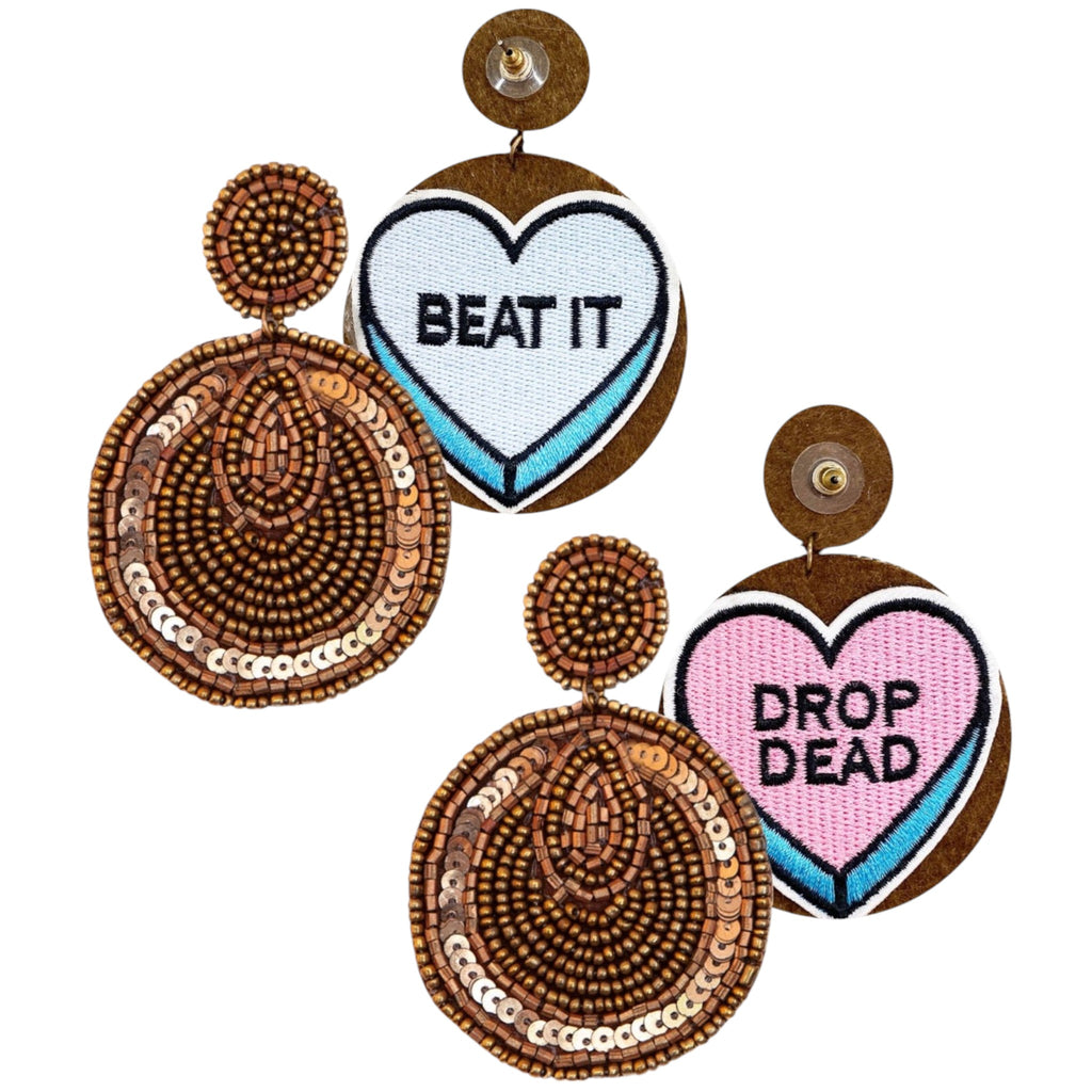 Bold statement earrings featuring intricate beadwork and cheeky embroidered heart designs with phrases 'BEAT IT' and 'DROP DEAD.'