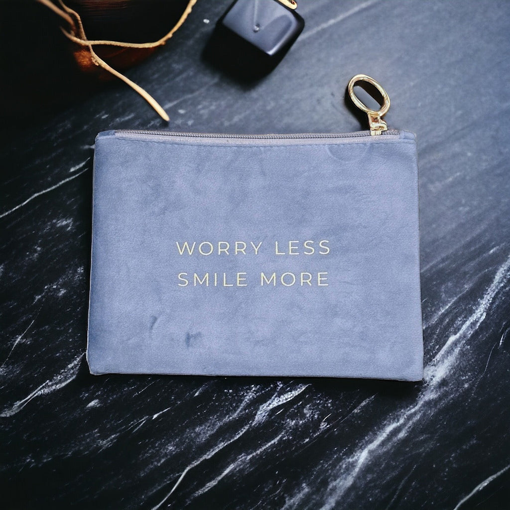 Chic and stylish suede pouch with "Worry Less, Smile More" sentiment, perfect for keeping essentials organized.